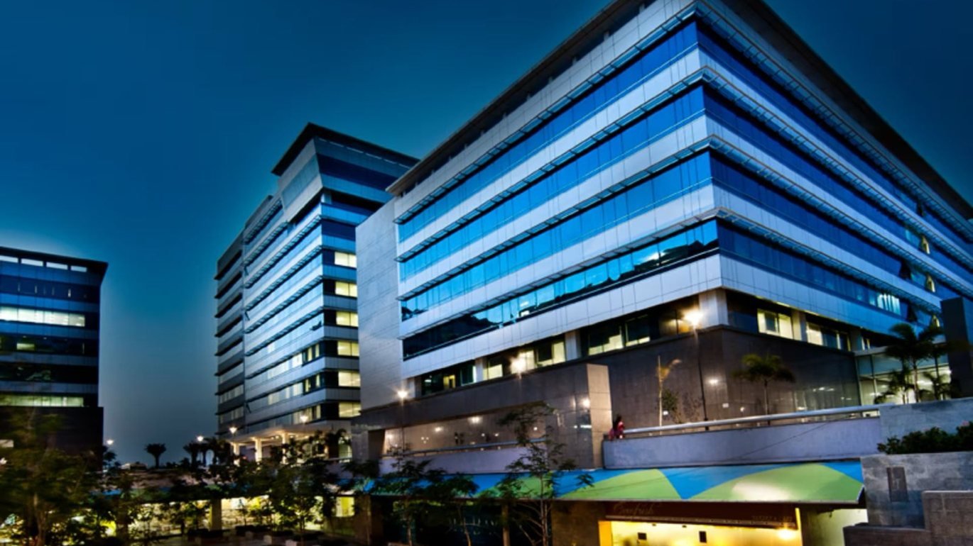 Blue-glass office towers at dusk with lit windows